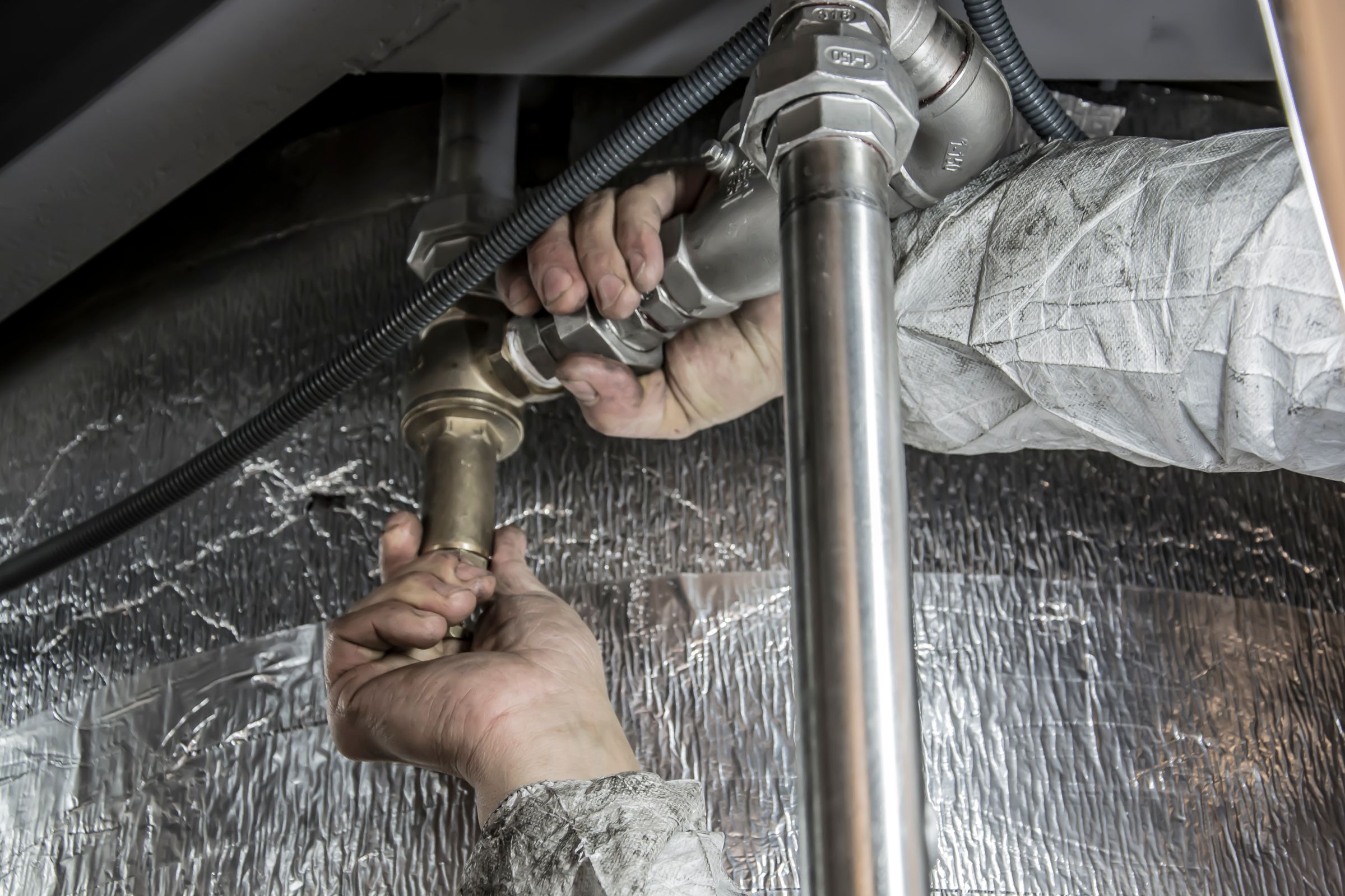 Hands working on metal pipe connections